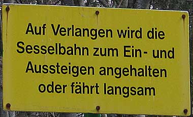 Auf Verlangen wird die Sesselbahn zum Ein- und Aussteigen angehalten oder fährt langsam weiter - Skiflugschanze Oberstdorf