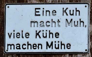 eine Kuh macht Muh, viele Kühe machen Mühe - Schild an einem Bauernhof in Wertach 2018