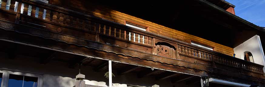 Balkon mit reich geschnitzten Figuren an einem Bauernhof in Grünenbach