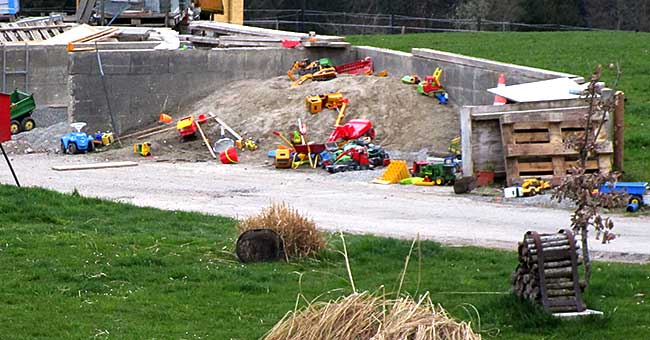 Ein typischer Sandspielkasten auf einem Bauernhof, den beioden Brüdern steht eine kleine Auswahl zur Verfügung