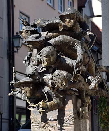 Brunnen "Verdruckte Allgäuer in Wangen" Alle verdruckten Allgäuer haben was typisch schwäbisches in der Hand: Kreuz, Spätzlehobel, Geldsack, Faschingsmaske, Spielkarten, Kerzenlicht, Wanderschuhe und Stock 