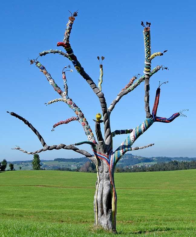 Der Traumzauberbaum - ein abgestorbener Birnbaum mit Flaschendeckeln verziert und mit Schnitzmessern bearbeitet - Kunst im Westallgäu